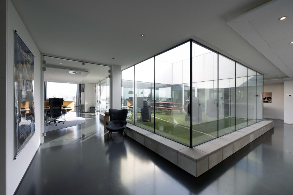 Modern office interior on Krijn Taconiskade with glass-walled courtyard and sleek furnishings.